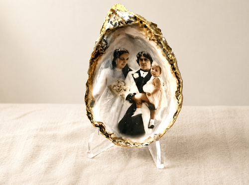 Vintage family photo transferred onto a gold-trimmed oyster shell keepsake on a clear display stand